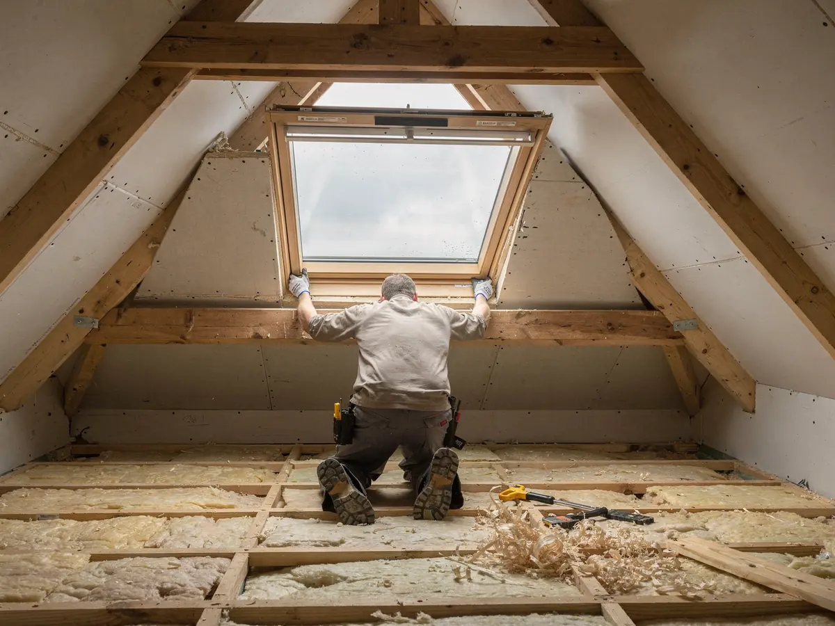 Fitter lifting a roof window into an opening from inside