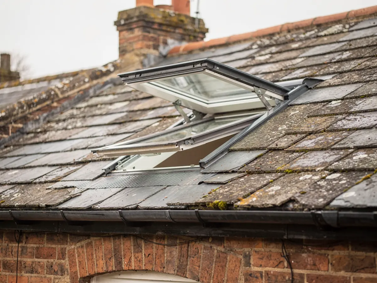 Top-hung roof window opened outwards on a slate roof